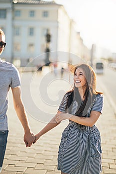 Happy young couple in love teenagers friends dressed in casual style walking together on city street