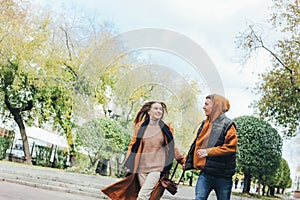 Happy young couple in love teenagers friends dressed in casual style walking together on the city street