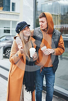 Happy young couple in love teenagers friends dressed in casual style walking together on city street in cold season