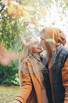 Happy young couple in love teenagers friends dressed in casual style walking together and throws leaves at camera, autumn city