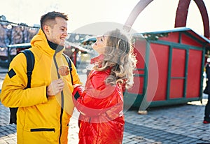 Happy young couple in love walking city street, looking at each other with smile, wearning in bright yellow and red down