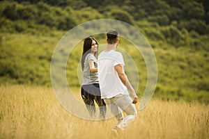 Happy young couple in love walking through grass field