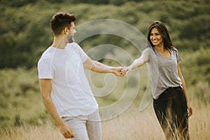 Happy young couple in love walking through grass field