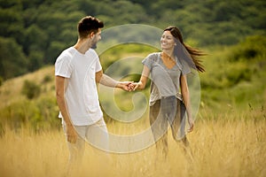 Happy young couple in love walking through grass field