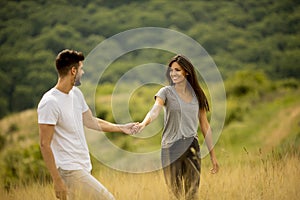 Happy young couple in love walking through grass field