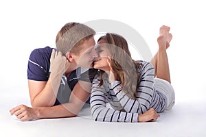 Happy young couple lying down on the floor and kissing