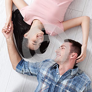 Happy young couple, lying on the floor, look at each other and dream of furniture for a new apartment. Mock up