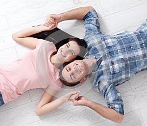 Happy young couple, lying on the floor, look at each other and dream of furniture for a new apartment. Mock up