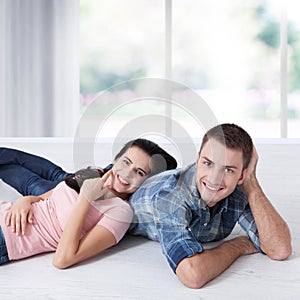 Happy young couple, lying on the floor, look at each other and dream of furniture for a new apartment. Mock up