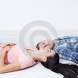 Happy young couple, lying on the floor, look at each other and dream of furniture for a new apartment. Mock up