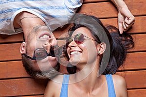 Happy young couple lying on a wooden floor