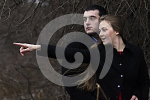 Happy young couple man looking where woman pointing in park