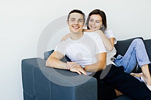 Happy young couple of man and woman embracing look at each other sitting on couch in living room