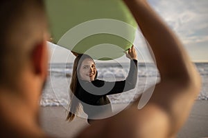 Happy Young Couple Man And Woman Surfing On The Beach