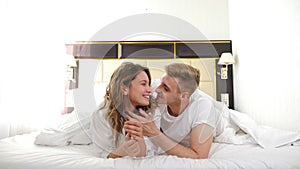 Happy young couple in morning. cheerful loving couple enjoying good time together on bed in bright bedroom. Happy lovers