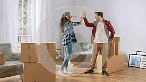 Happy Young Couple Moving in Into New Apartment, Carrying Cardboard Boxes with Stuff, Having Fun