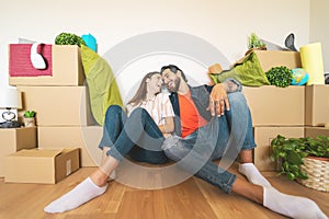 Happy young couple moving in new home first time - Man and woman having fun unpacking carton box in new property house