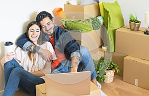 Happy young couple moving in new home first time - Man and woman having fun using computer next carton box in new property house