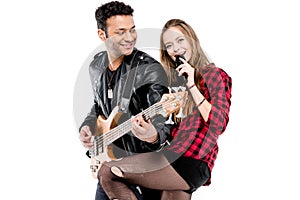 Happy young couple of musicians with microphone and electric guitar performing music together