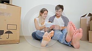 Happy young couple ordering furniture on the tablet to their new apartment