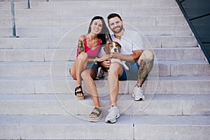 Happy young couple outdoors with beagle dog. Family and lifestyle concept