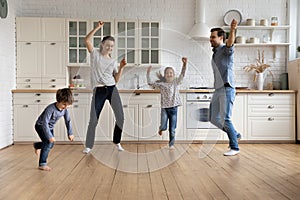 Happy young couple parents dancing with small kids.