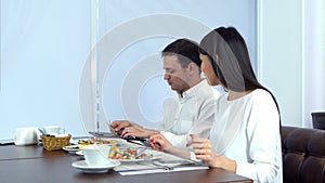 Happy young couple paying bill brought by waiter and leaving cafe