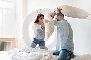 Happy young couple pillows fight and laughing on bed.