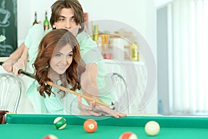 Happy young couple playing billiard