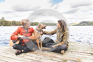 Happy young couple playing with dog on a dock