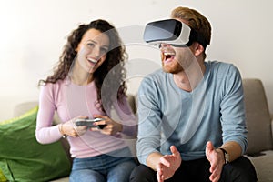 Happy young couple playing video games with virtual reality headsets