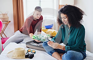 Happy young couple preparing and packing for summer holiday at home.