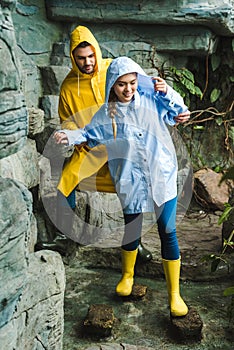 happy young couple in raincoats walking