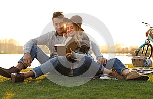 Happy young couple reading book while having picnic