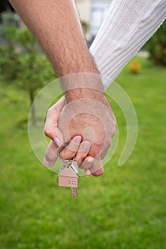 A happy young couple rejoices in buying an apartment, the couple holds in their hands the keys to their new house, a metal