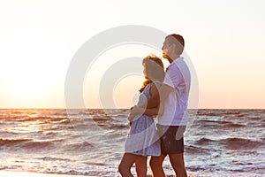 Happy young couple relaxing on beach at sunset. Dream vacation.