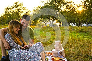 Happy young couple relaxing and having picnic in park. Peaceful sweet couple enjoying dinner in park. Man and woman