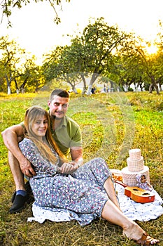 Happy young couple relaxing and having picnic in park. Peaceful sweet couple enjoying dinner in park. Man and woman sitting on