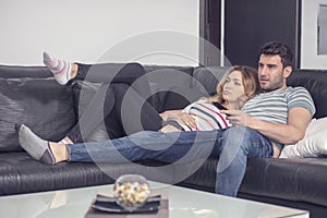 Happy young couple relaxing and watching TV at home.