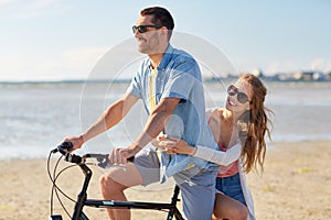 Happy young couple riding bicycle on beach