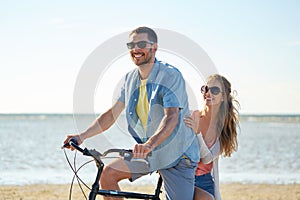 Happy young couple riding bicycle on beach