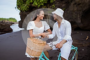 happy young couple riding bicycles on beach