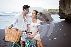 happy young couple riding bicycles on beach