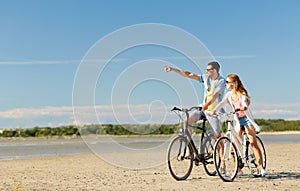 Happy young couple riding bicycles at seaside