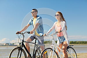 Happy young couple riding bicycles at seaside