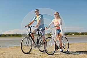 Happy young couple riding bicycles at seaside