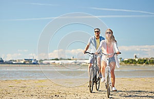 Happy young couple riding bicycles at seaside