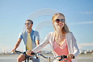 Happy young couple riding bicycles at seaside