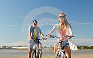 Happy young couple riding bicycles at seaside