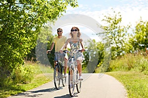 Happy young couple riding bicycles in summer